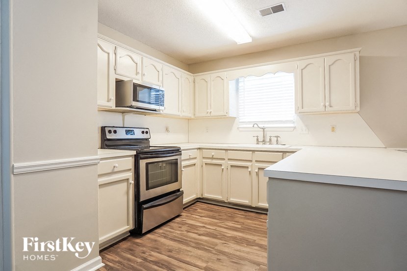 a kitchen with white cabinets and a stove and a microwave