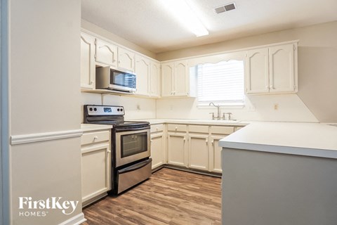 a kitchen with white cabinets and a stove and a microwave