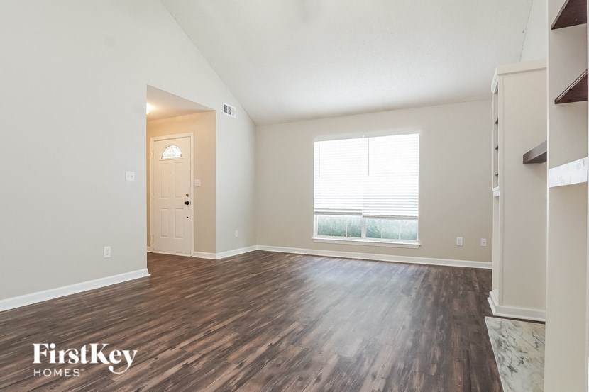 the living room of an apartment with wood flooring and a window