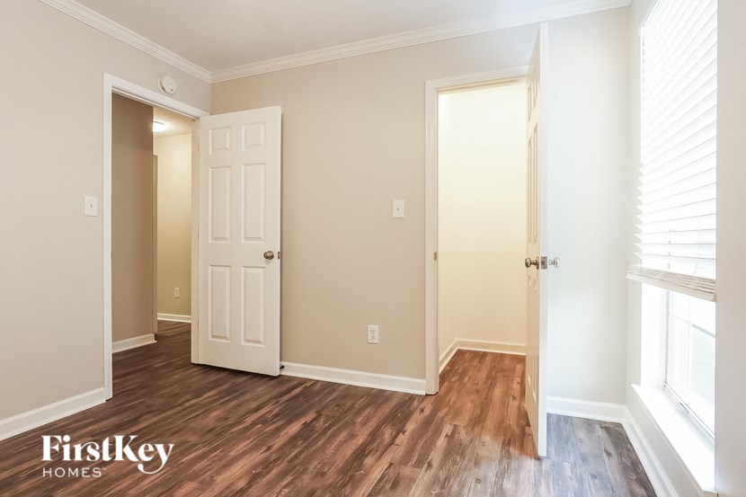 a bedroom with wood flooring and a door to a closet