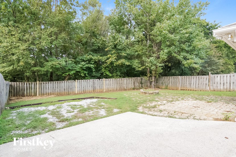 a backyard with a white fence and a yard with grass and trees