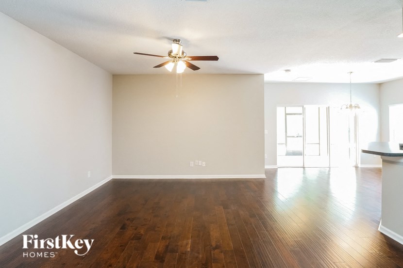 an empty living room with wood floors and a ceiling fan