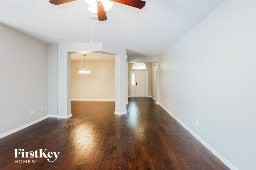 a living room and dining room with wood floors and a ceiling fan