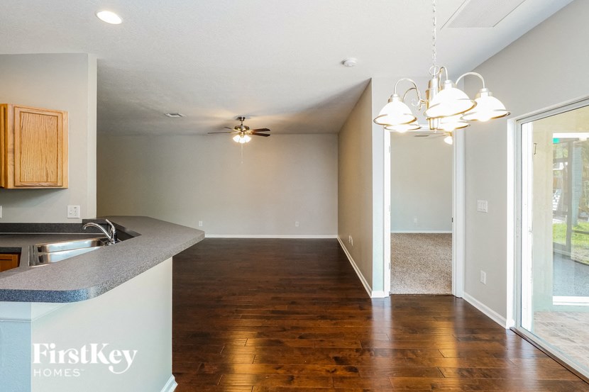 an empty living room with a kitchen and a ceiling fan
