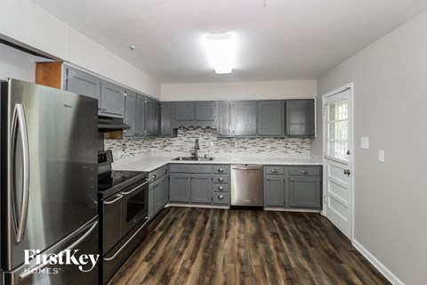 A kitchen with a refrigerator and wooden floors.