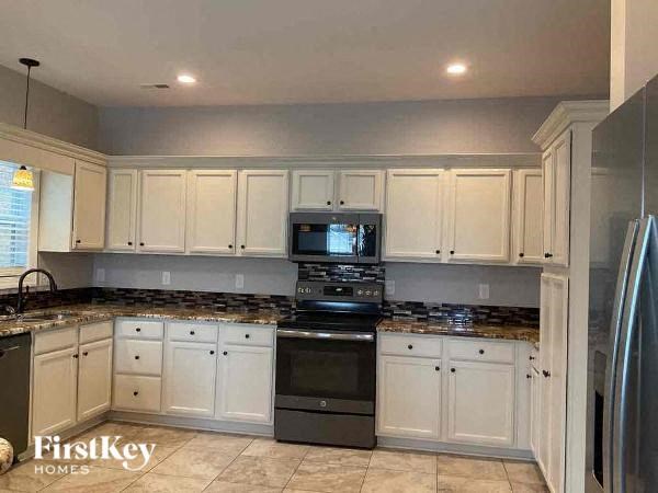a kitchen with white cabinets and black appliances