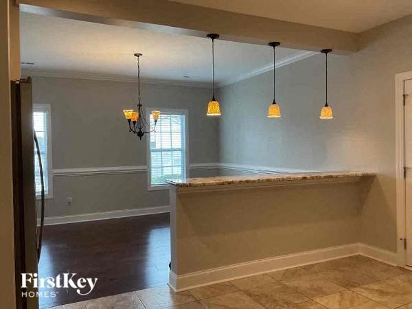 an empty living room with three lamps hanging from the ceiling