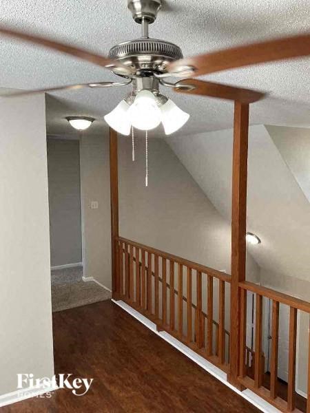 A room with a ceiling fan and a wooden railing.