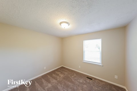 the upstairs bedroom with carpet and a window