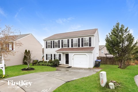 A house with a garage and a driveway in front of it.