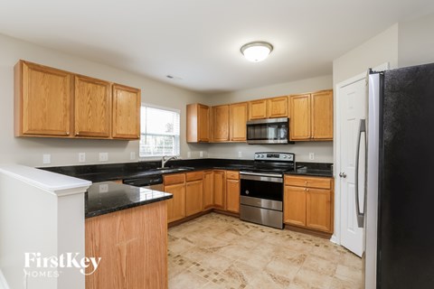 A kitchen with wooden cabinets and black countertops.
