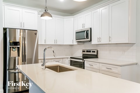 A kitchen with white cabinets and a stainless steel refrigerator.