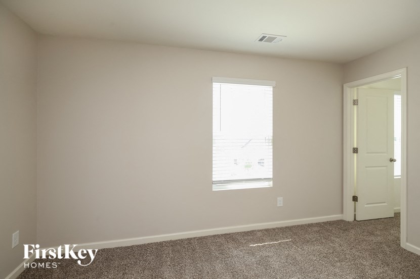 a bedroom with white walls and a window