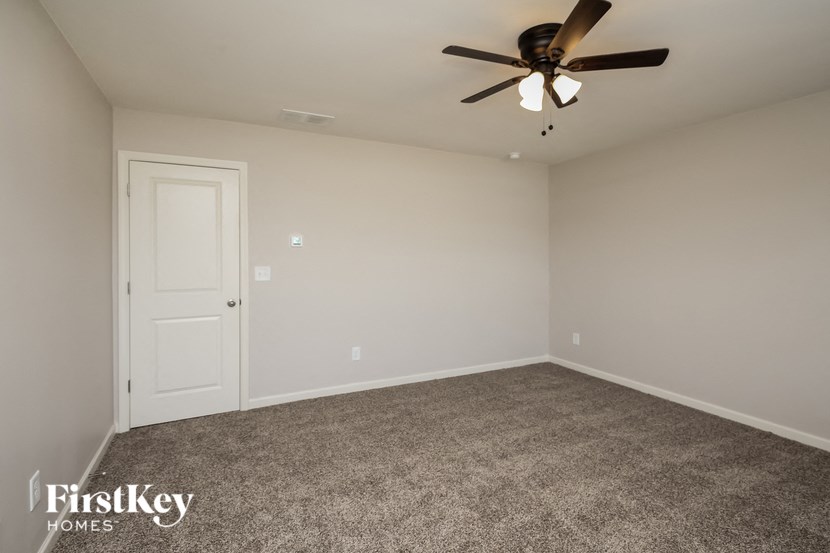 a empty living room with a ceiling fan and carpet