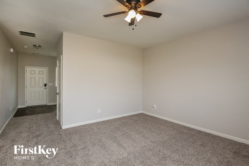 the living room of an empty house with a ceiling fan