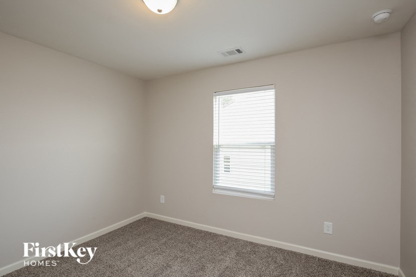 a bedroom with white walls and a window