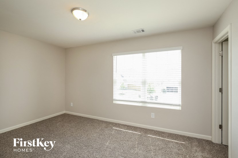 a bedroom with a large window and a carpeted floor