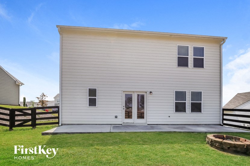 the exterior of a small white house with a porch and a lawn