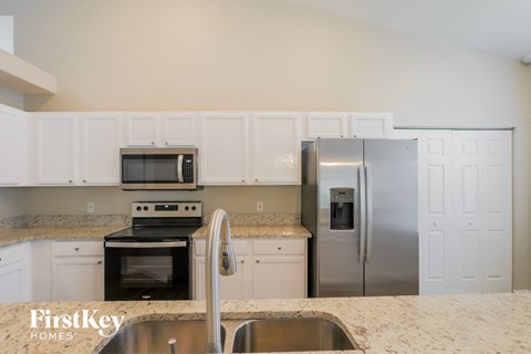 A kitchen with a stove, oven, refrigerator, and sink.