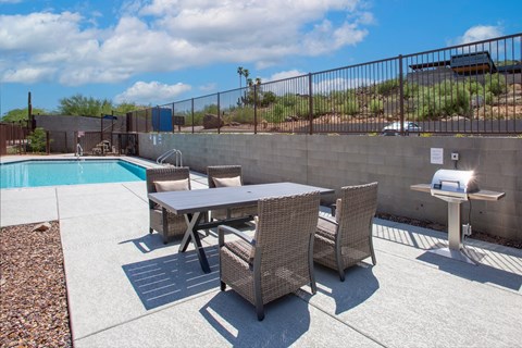 a patio with a table and chairs next to a pool