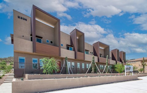 a row of modern apartments with a blue cloudy sky in the background