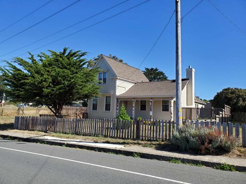A house with a white fence and a tree in front of it.