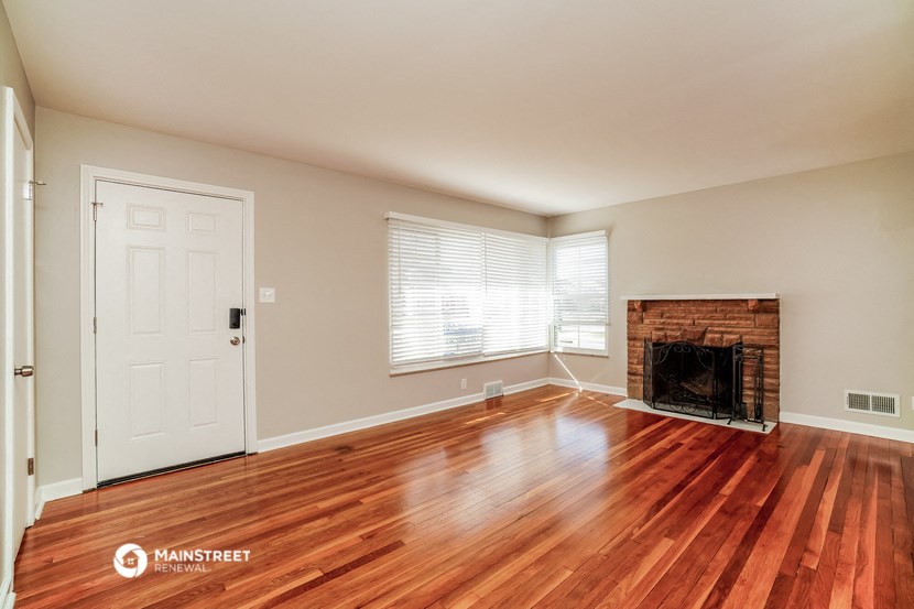an empty living room with a fireplace and wooden floors