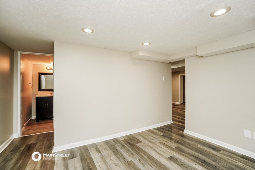 an empty living room with white walls and wood flooring