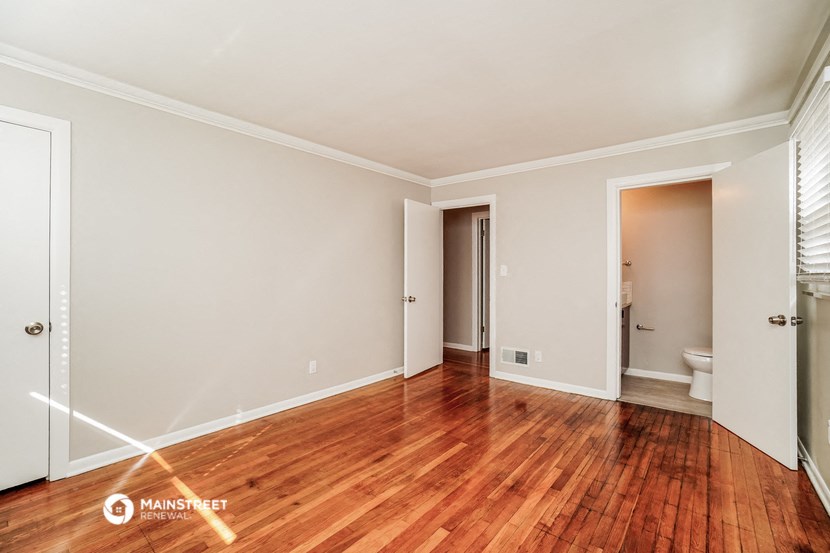 an empty living room with wood flooring and a toilet