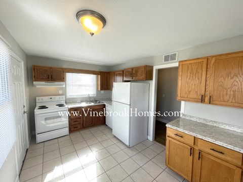A kitchen with white appliances and wooden cabinets.