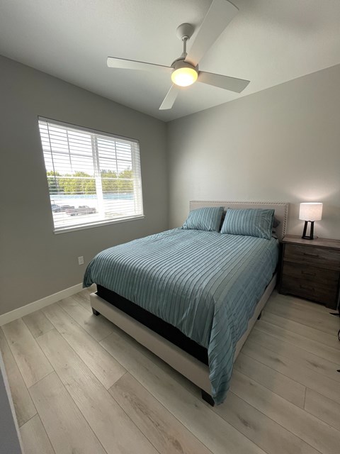 A bedroom with a bed, nightstand, and window.