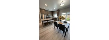 Modern kitchen with wood floors, granite counters, stainless appliances, sliding glass door, barstools, and dining table