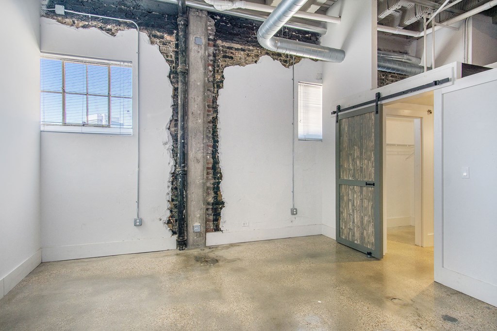 an empty room with a door in the corner and a exposed brick wall
