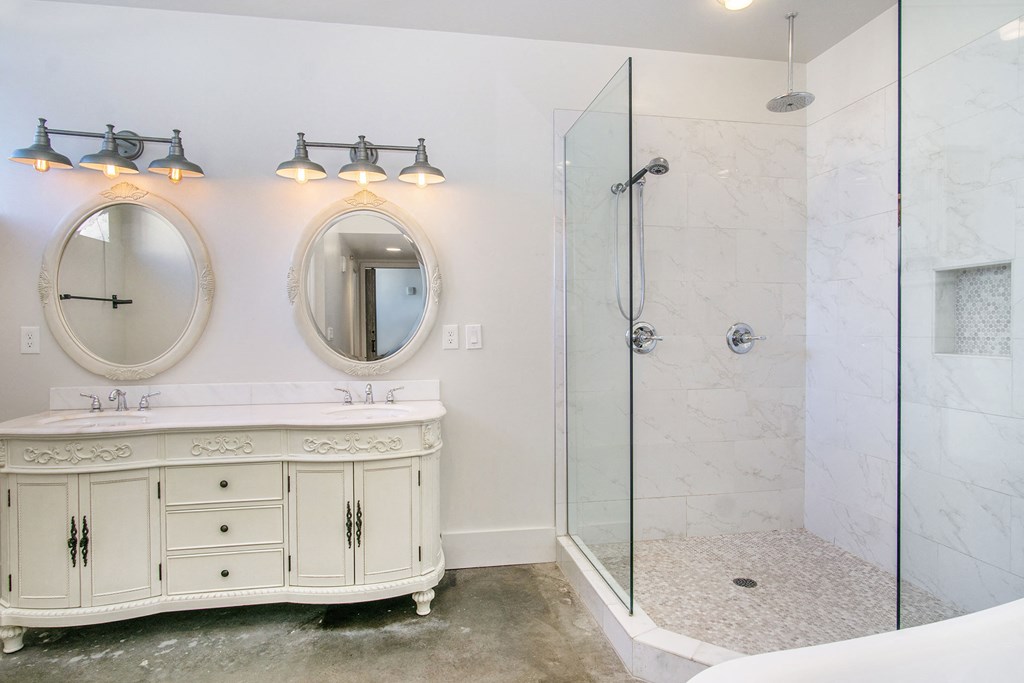 a bathroom with two mirrors and a shower and a sink