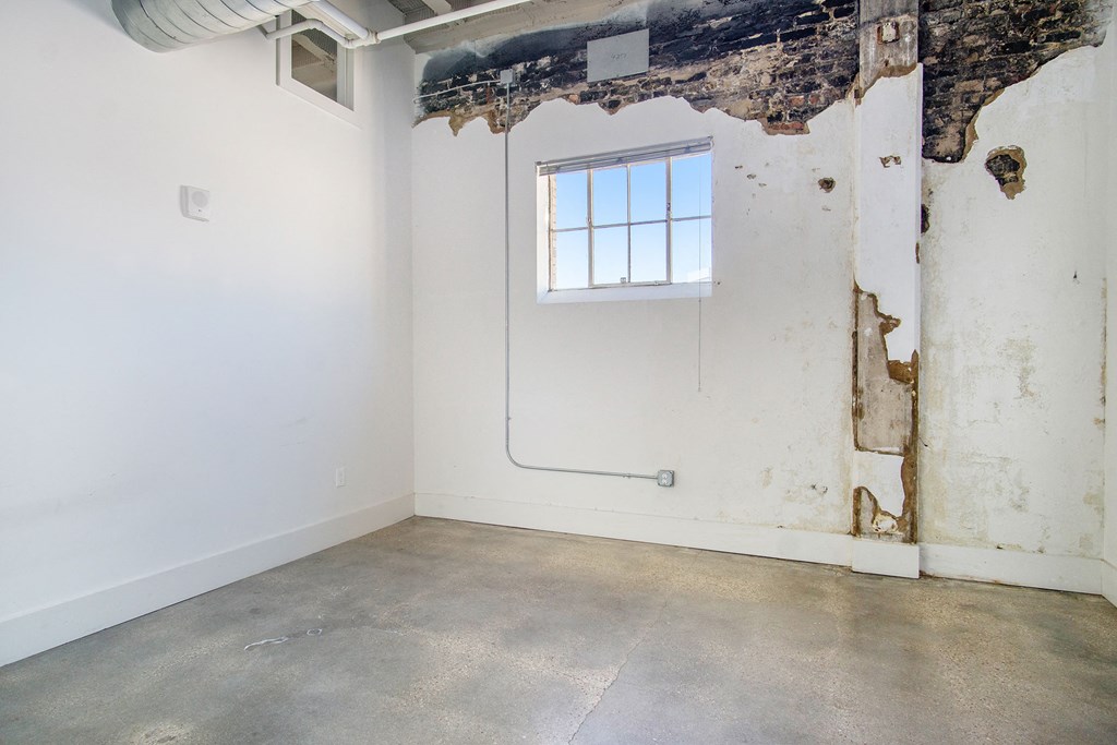 an empty room with a window in the wall and a cement floor