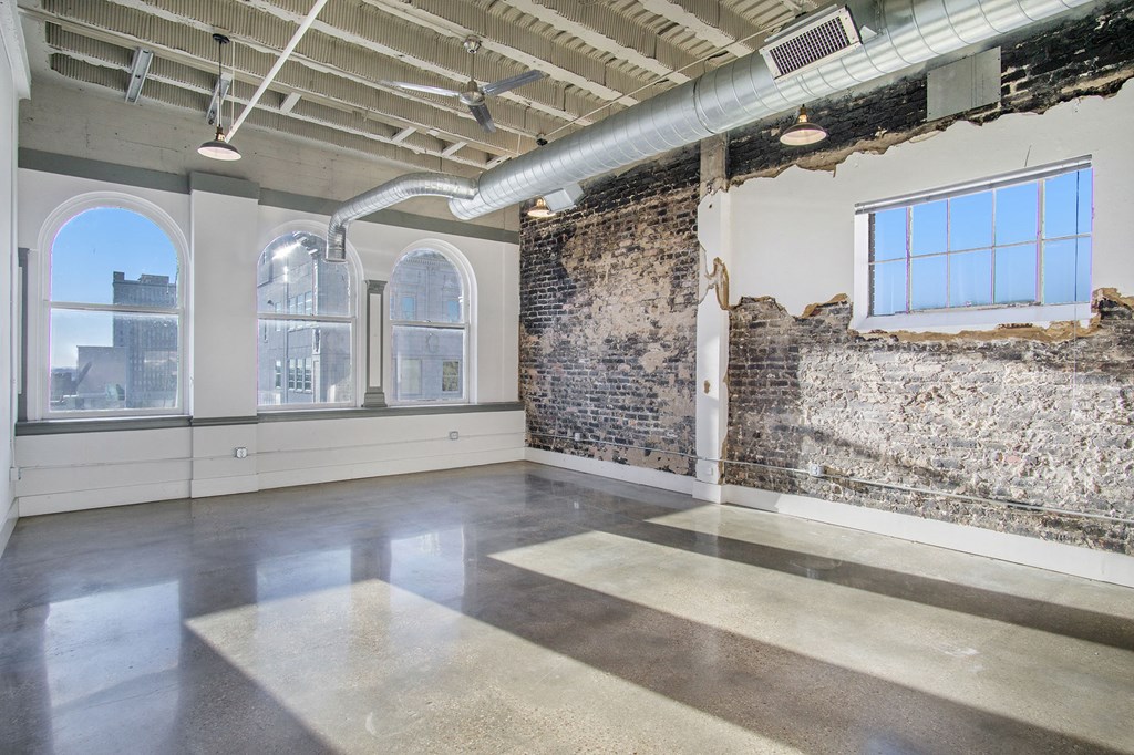an empty room with an exposed brick wall and a large window
