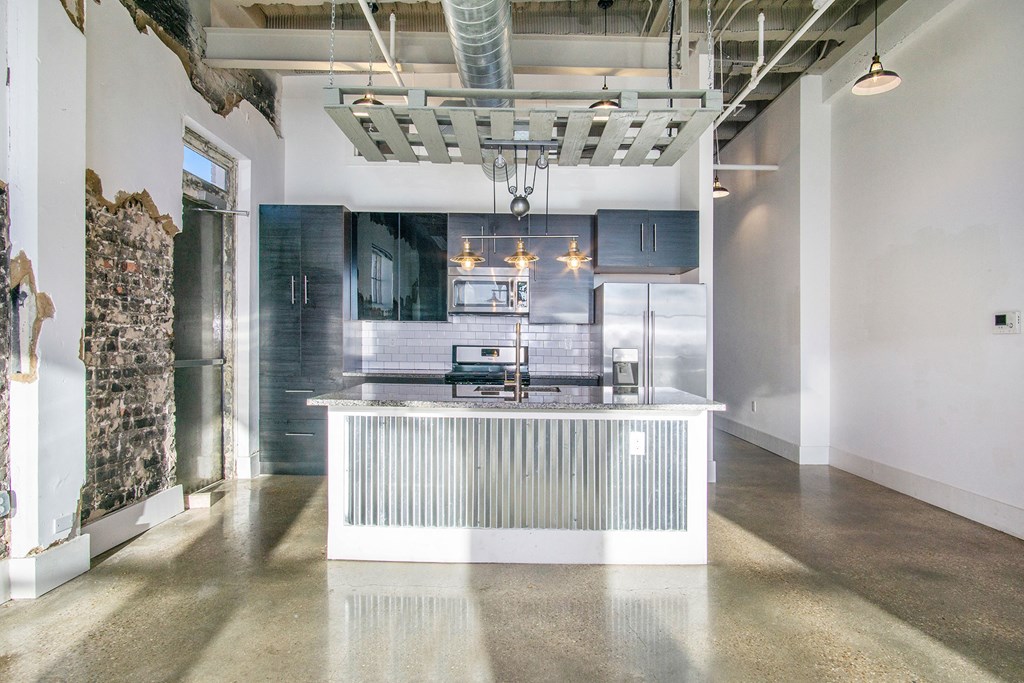 a large kitchen with a white island and a stainless steel refrigerator