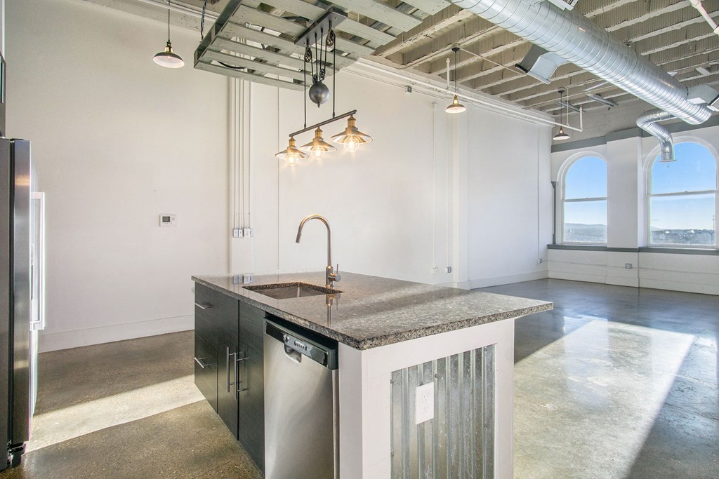 a kitchen with a sink and a counter top in a room with a large window