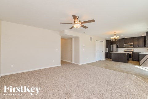 A spacious living room with a ceiling fan and a dining area in the background.