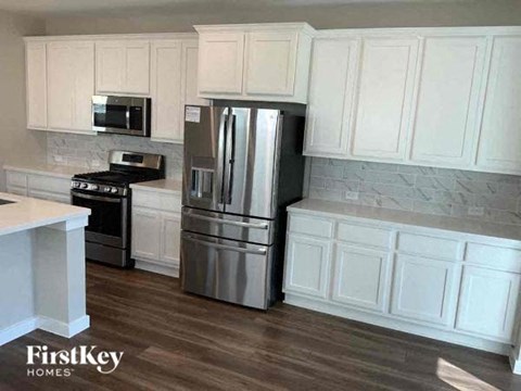 A kitchen with white cabinets and a stainless steel refrigerator.