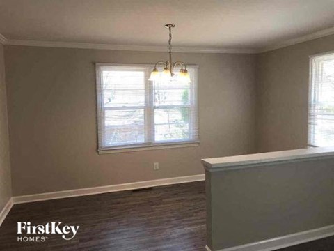 an empty living room with a window and a chandelier