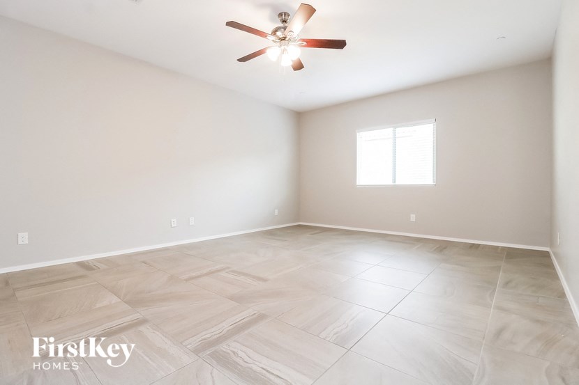 a clean empty room with a ceiling fan and a window