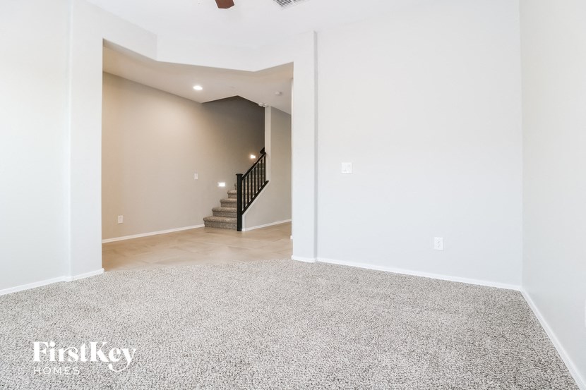 the living room and dining room with carpeted stairs and white walls