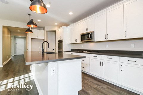 A kitchen with white cabinets and a black countertop.