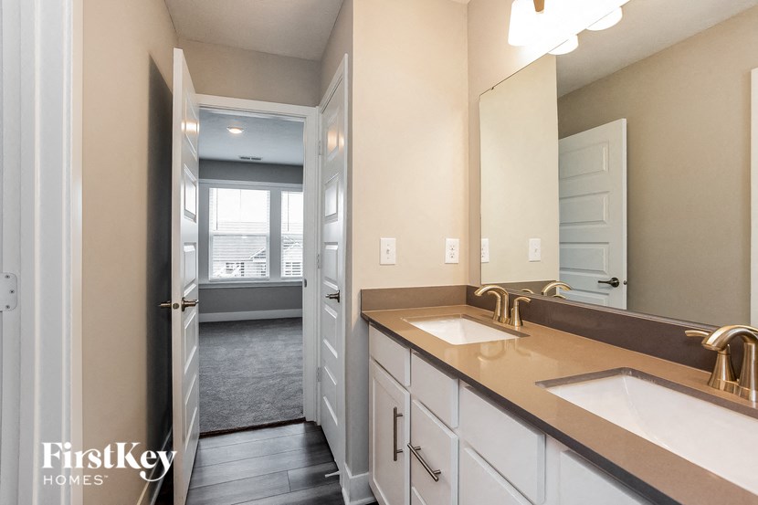 a bathroom with two sinks and a doorway to a bedroom
