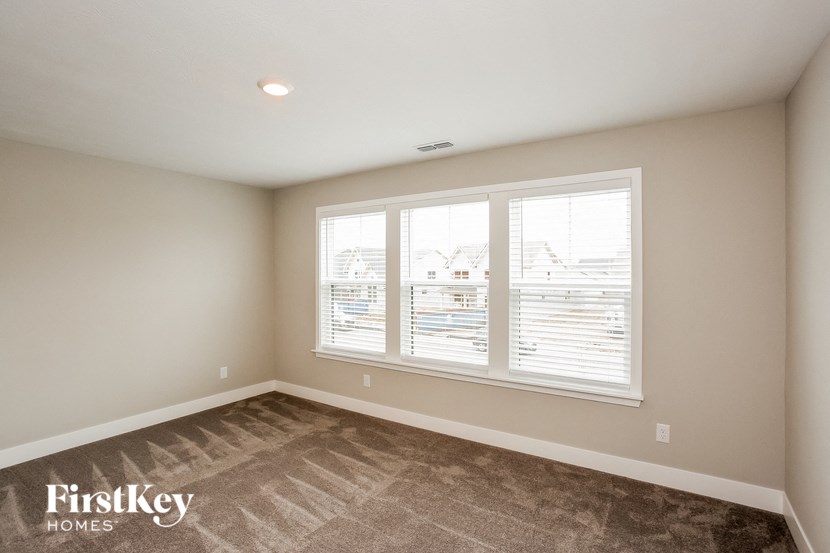 a bedroom with three windows and a carpeted floor