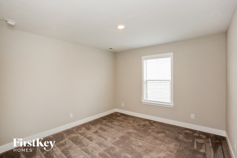 the bedroom of a home with a carpeted floor and a window