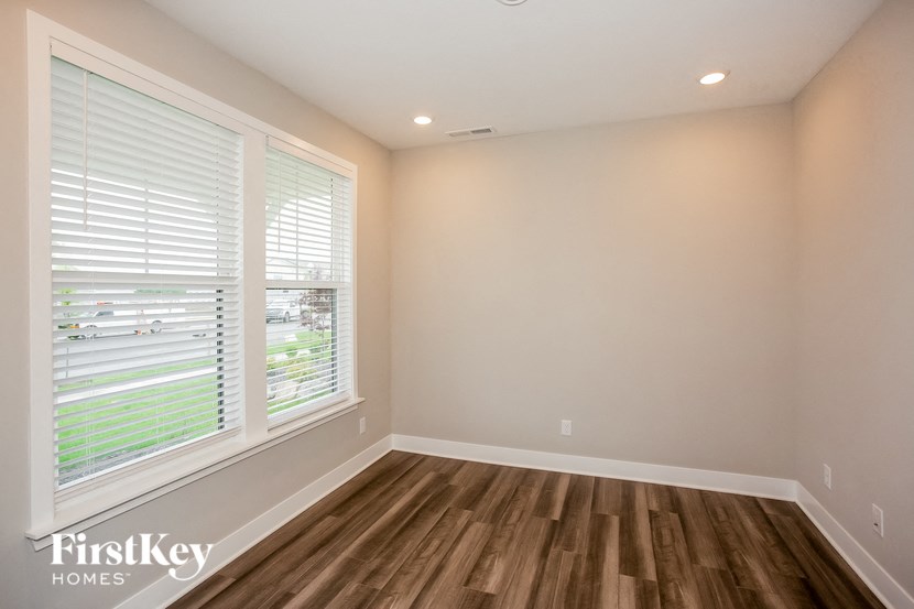 an empty living room with a large window and wooden floors