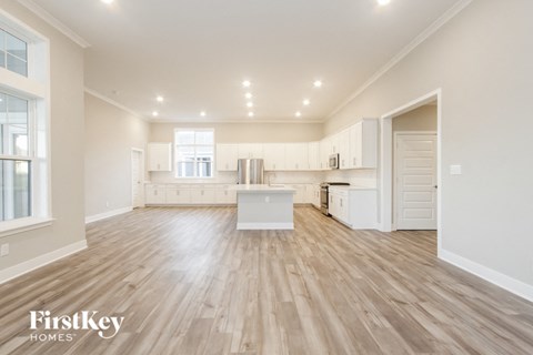 an open kitchen and living room with white cabinets and wood flooring