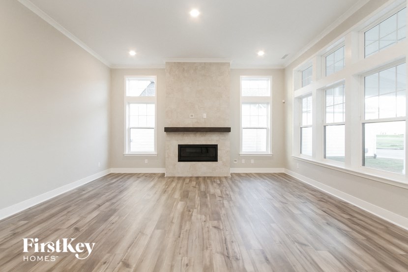 an empty living room with a fireplace and wooden floors
